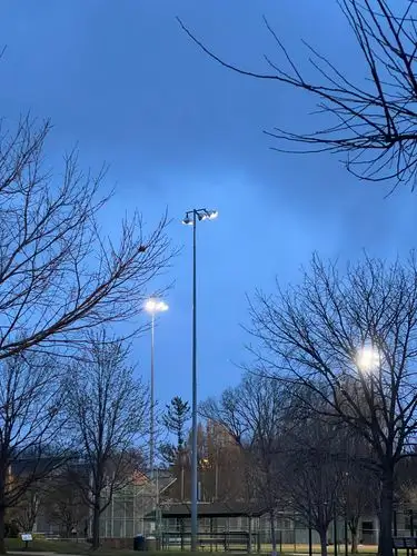 Stadium lights ignite the twilight sky.